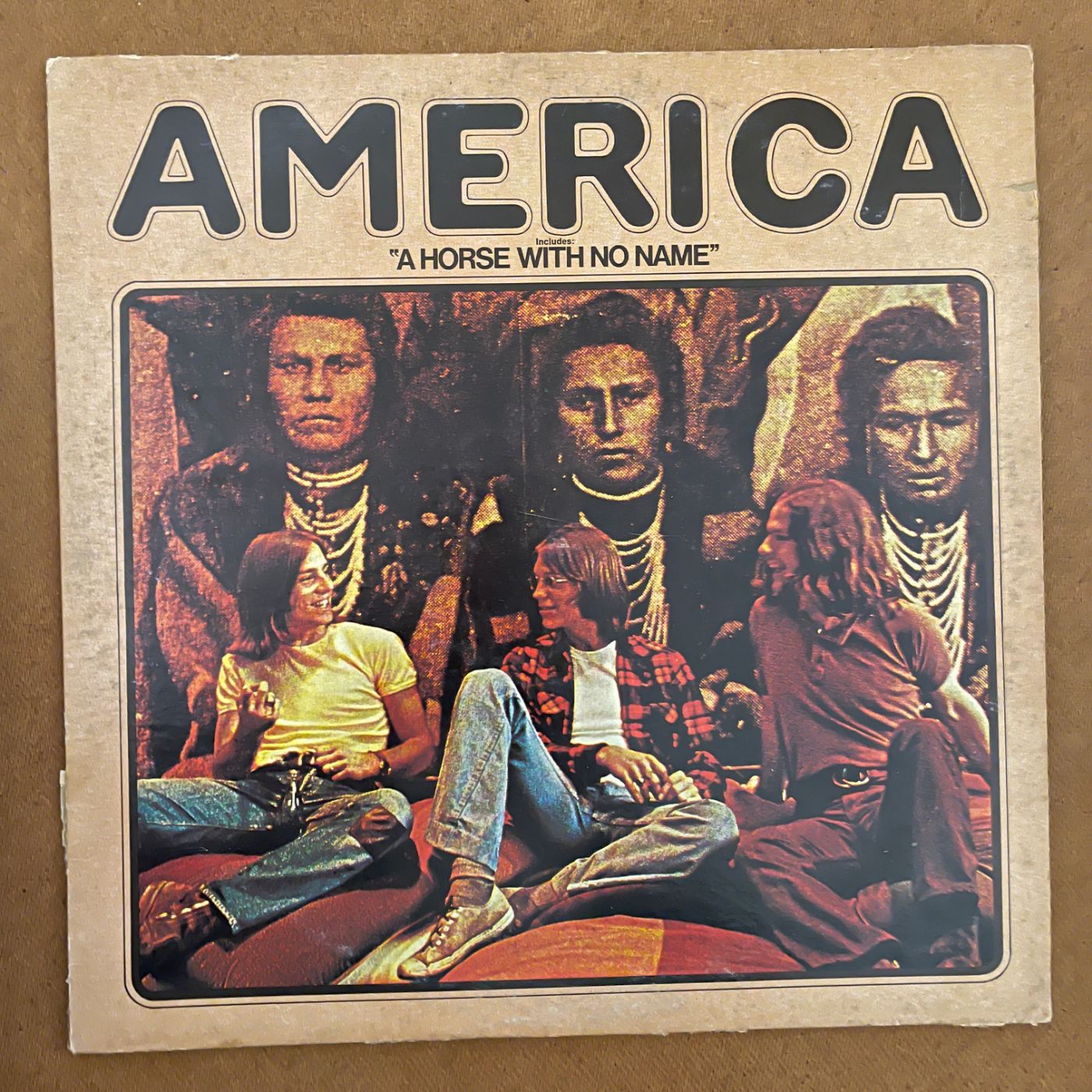 America cover art for vinyl record album has an native America Navaho sitting as though he’s unhappy, dressed in ceremonial dress