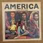 America cover art for vinyl record album has an native America Navaho sitting as though he’s unhappy, dressed in ceremonial dress